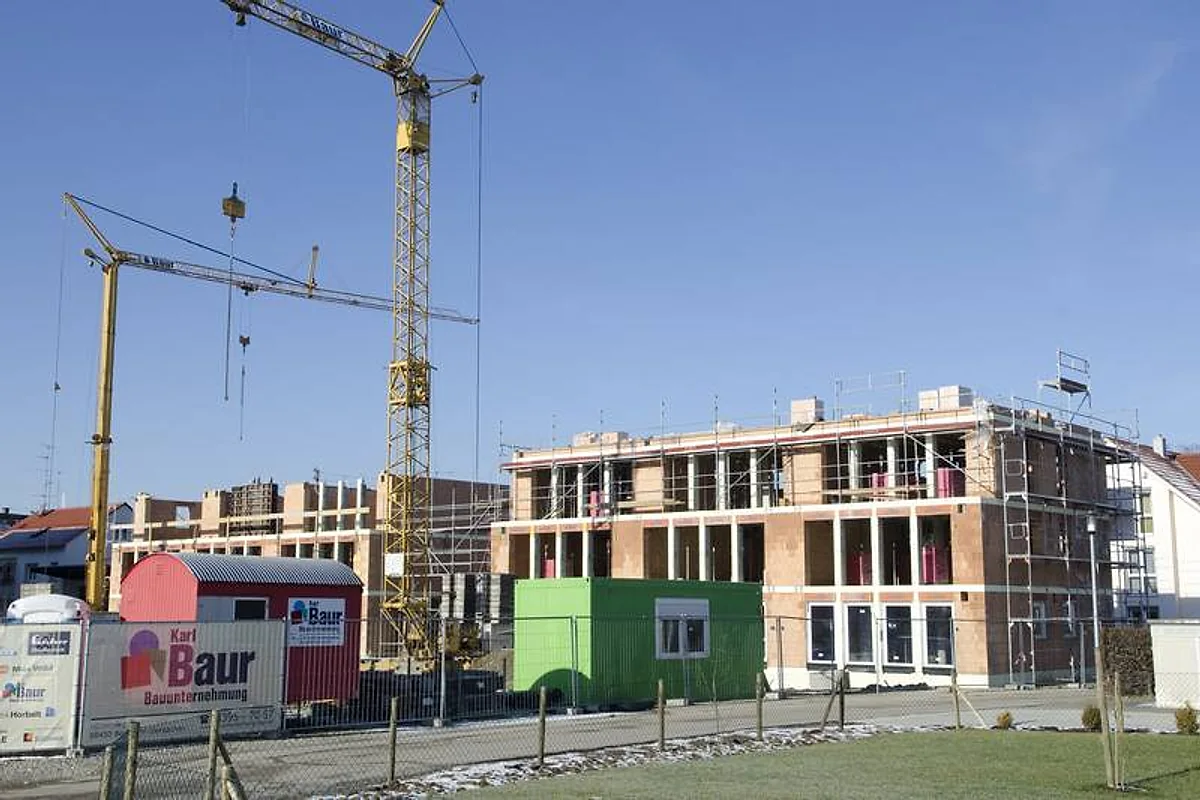 Mehrgeschossiger Rohbau mit Baukränen und Baur-Baucontainer