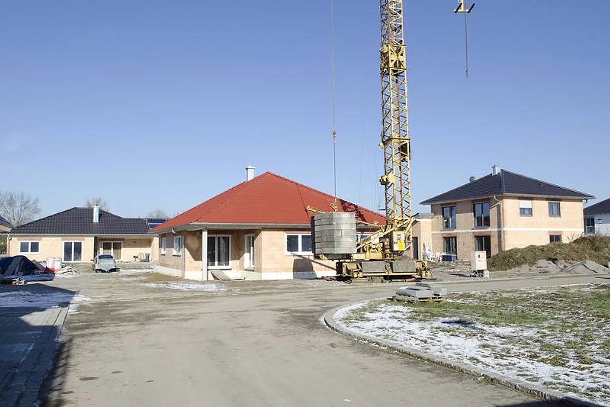 Wohnbaustelle mit Kran und leicht verschneitem Gelände